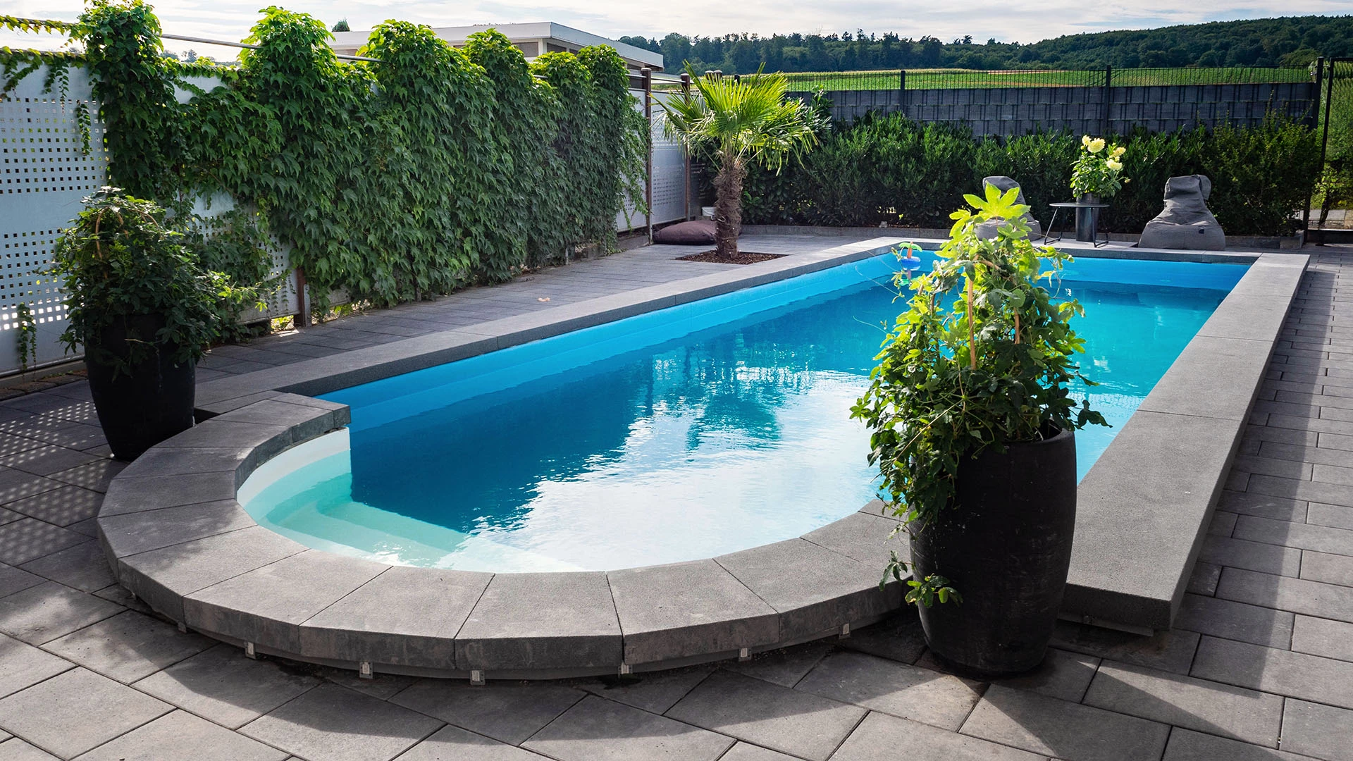 Pool selber gebaut im eigenen Garten mit moderner grauer Umrandung 