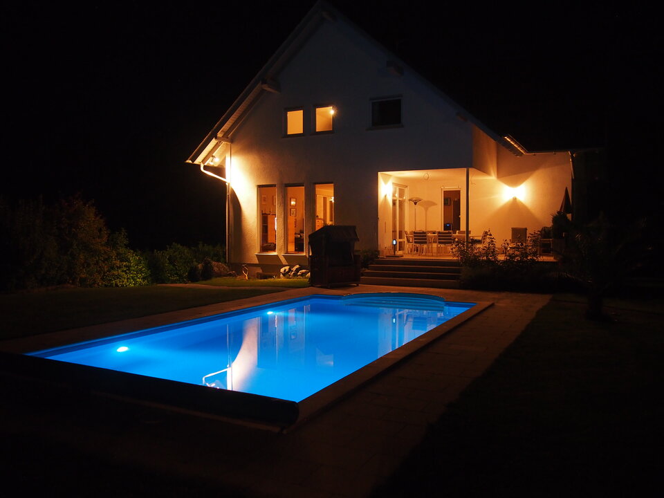 Selbst gebauter Pool mit LED Poolbeleuchtung im Garten bei Nacht.